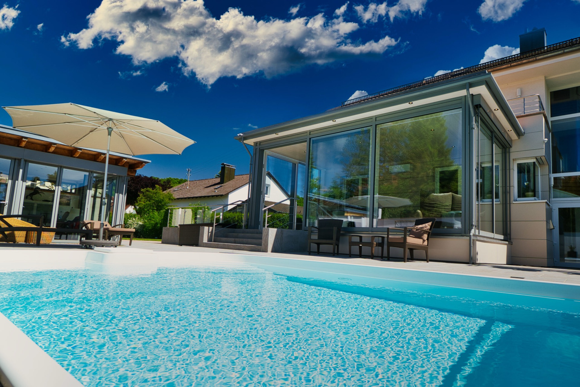 Moderner Glas-Wintergarten an einem Haus mit angrenzendem Swimmingpool.